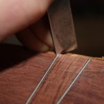 A chisel cuts a mitre into the black white black binding strips